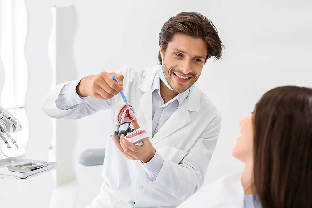 cheerful doctor showing how to brush teeth