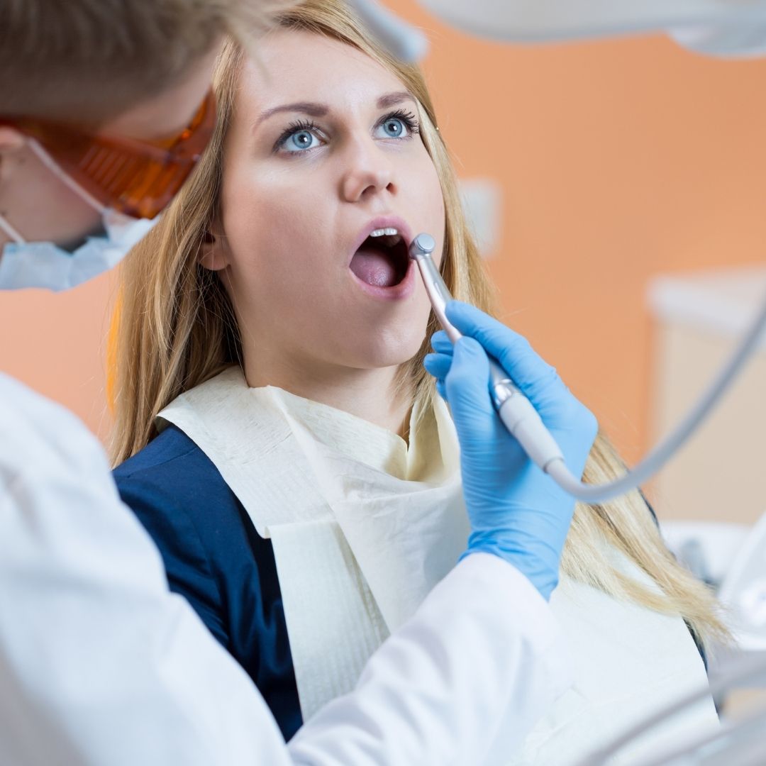 Lady Opening her mouth whilst dentist performs root canal treatment | | Featured image for Root Canal Aftercare | Blog